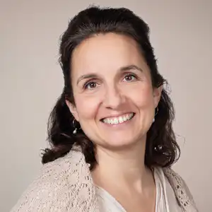 Head-and-shoulders portrait of a smiling woman with dark hair, wearing a light cardigan, facing the camera